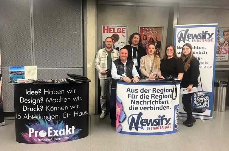 Kolleginnen und Kollegen aus der Newsify-Redaktion, der Anzeigenberatung und der Werbetechnik posieren am Messestand in der Volkswagenhalle
