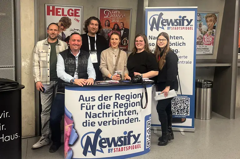 Kolleginnen und Kollegen aus der Newsify-Redaktion, der Anzeigenberatung und der Werbetechnik posieren am Messestand in der Volkswagenhalle
